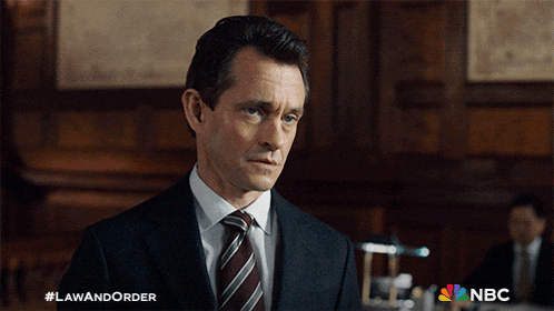 a man in a suit and tie stands in front of a sign that says law and order