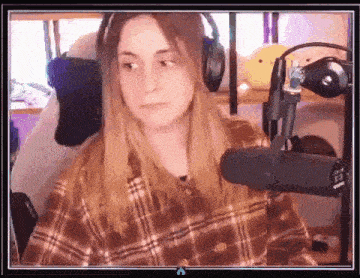 a woman in a plaid shirt is sitting in front of a microphone and headphones .