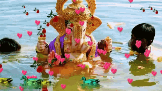 a statue of ganesha is surrounded by hearts and flowers in the water