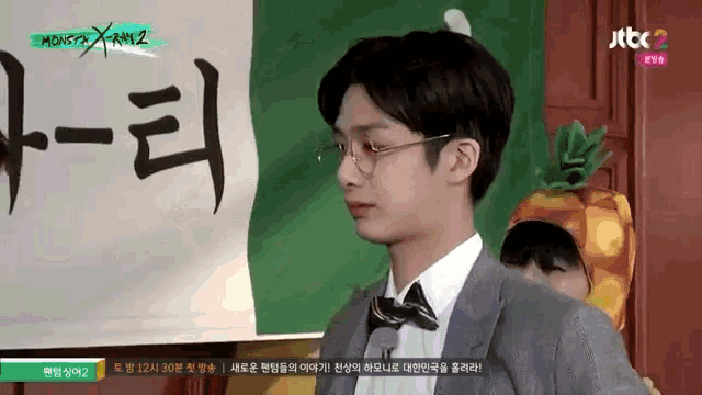 a man in a suit and bow tie stands in front of a sign that says jtcc2 on it