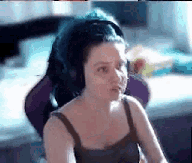 a woman is sitting in a chair wearing headphones and making a funny face .