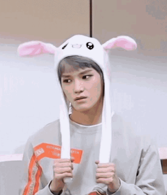 a young man wearing a bunny hat with moving ears is making a funny face .