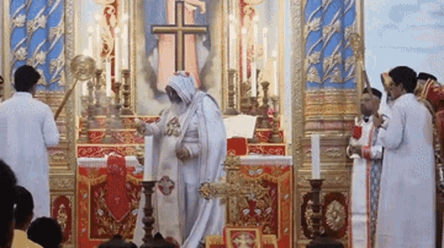 a woman in a white robe stands in front of an altar with candles and a cross on it