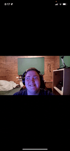 a phone screen shows a man wearing headphones and smiling with the time 8:17