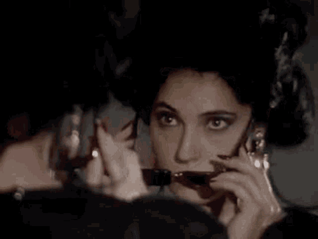 a woman is wearing sunglasses and looking at herself in the mirror .