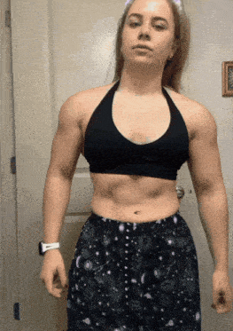 a woman in a black top and black shorts stands in front of a white door