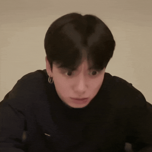 a close up of a person 's face with a black shirt and hoop earrings