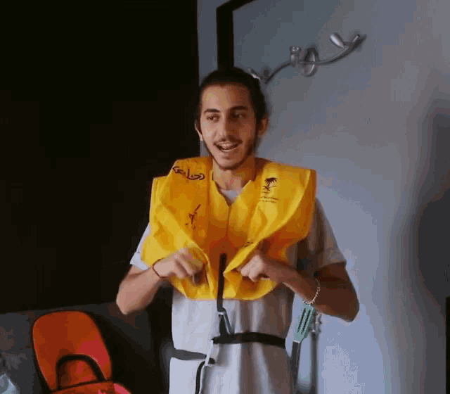 a man is wearing a yellow life jacket with the word saudi on it