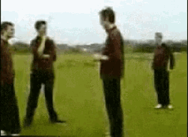 a group of men are standing in a field talking to each other