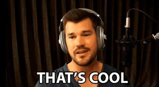 a man wearing headphones is standing in front of a microphone and says that 's cool
