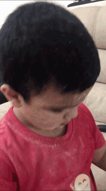 a young boy in a red shirt with an emoji on it