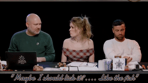 a man and a woman sit at a table with maybe i should lick it like the fish