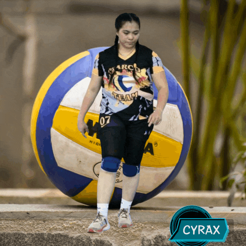 a woman standing next to a volleyball with the name cyrax on the bottom