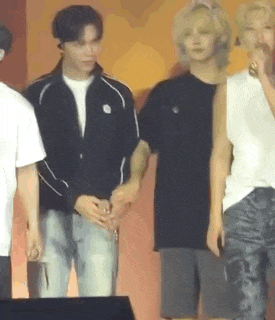 a group of people are standing next to each other on a stage holding hands .
