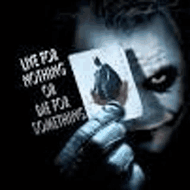 the joker is holding a playing card in front of his face with a quote on it .