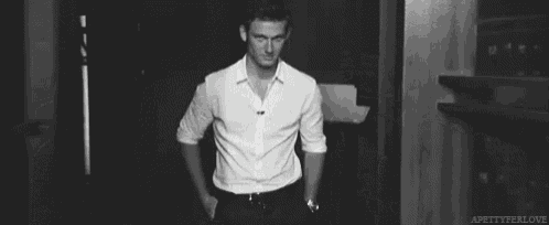 a man in a white shirt and black pants is waving his hand in a black and white photo .