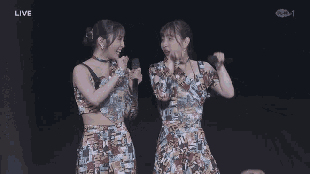 two women singing in front of microphones with the word live on the bottom
