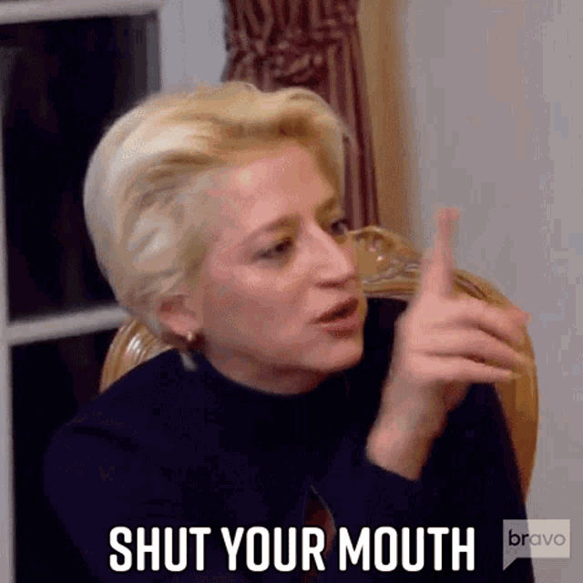 a woman is sitting in a chair and pointing at the camera while talking .