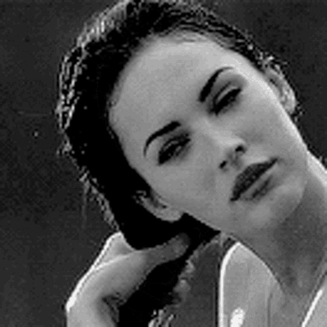 a black and white photo of a woman holding her hair in a braid .