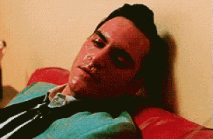 a man in a suit and tie is laying on a red couch