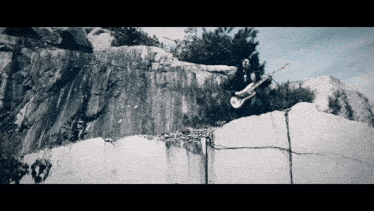 a man playing a guitar on top of a rocky cliff