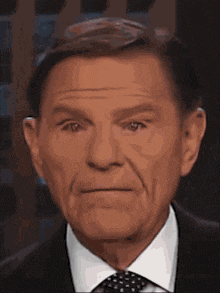 a man in a suit and tie is looking at the camera .