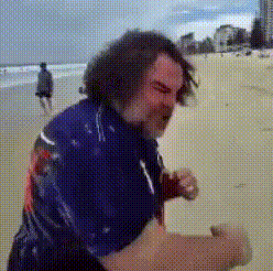 a man in a blue shirt is standing on a beach .