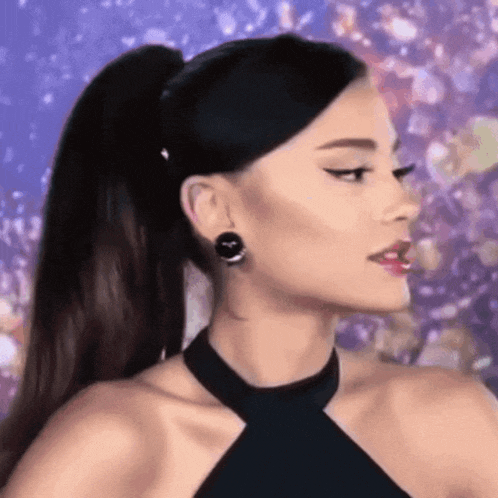 ariana grande is wearing a ponytail and earrings while standing in front of a purple background .