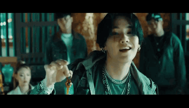 a man in a green jacket is holding a key in his hand in a dark room .