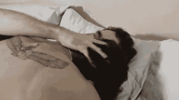 a man with a tattoo on his back is laying in bed .