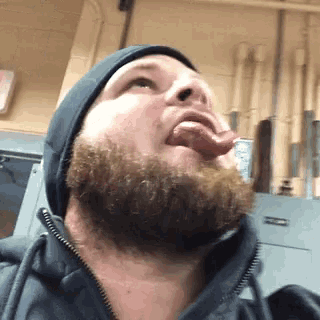 a man with a beard is sticking his tongue out while wearing a beanie