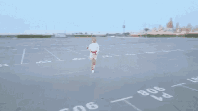 a woman is running in an empty parking lot with the numbers 808 on the ground