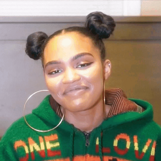 a woman wearing a green sweater that says one love on it
