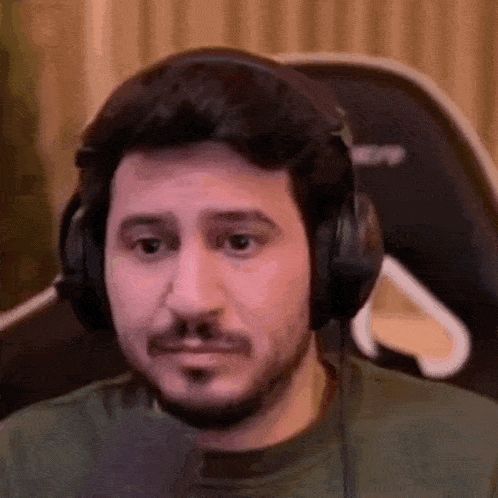 a man with a beard is wearing headphones and making a face .