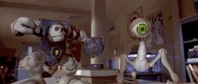 two toys are standing next to each other in a room . one of the toys has a green eye .