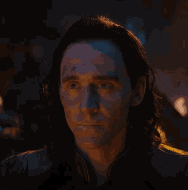 a close up of a man 's face with long hair and a dark background