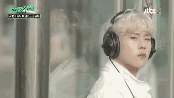 a man wearing headphones is standing in front of a window .