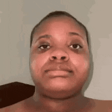 a woman without a shirt is making a funny face with her eyes closed .