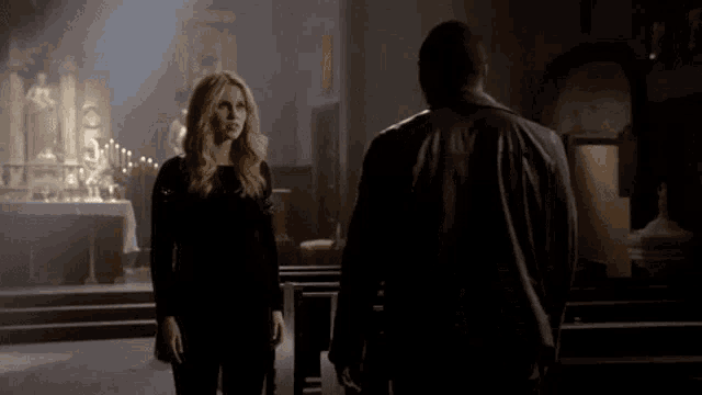 a man and a woman are standing in a church and looking at each other .