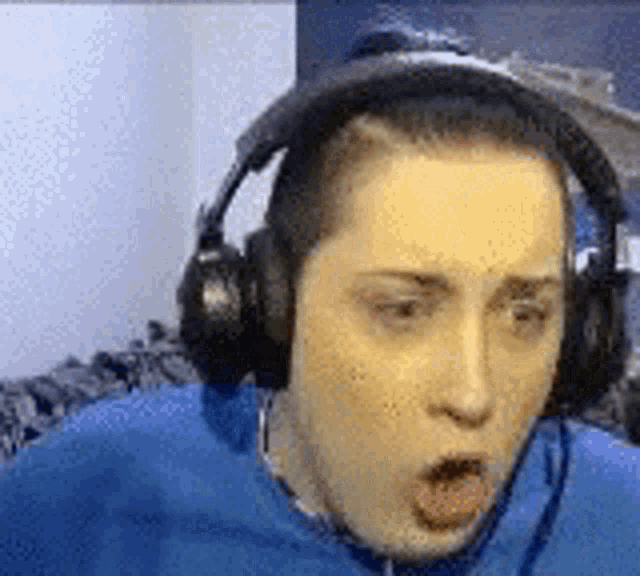 a man is wearing headphones and making a surprised face .