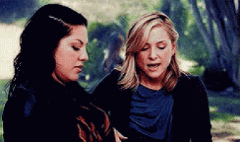 two women are standing next to each other in a park and talking to each other .