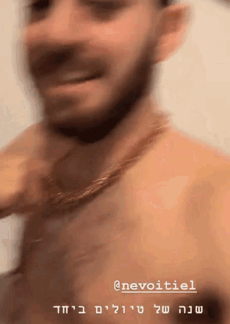 a man without a shirt is wearing a gold chain around his neck and the name nevoitiel is on the bottom