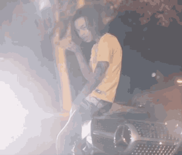a man in a yellow shirt is standing next to a mercedes car