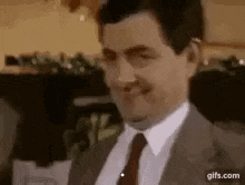 a man in a suit and tie is smiling and making a funny face .