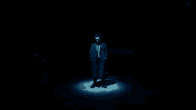 a man in a suit and tie is standing in front of a car in a garage