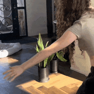 a woman with curly hair is standing in front of a plant