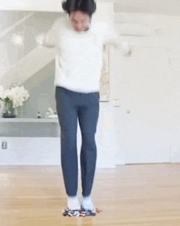 a man is jumping in the air while wearing a white sweater and blue pants .