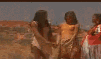 a woman in a white dress is riding a white horse in the desert .