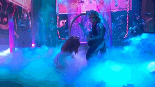 a man is playing a guitar in front of a woman in a hoop on a stage