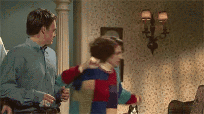 a man in a blue shirt is standing next to another man in a colorful sweater .